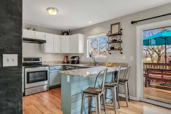 a kitchen with kitchen island a stove a table and chairs in it