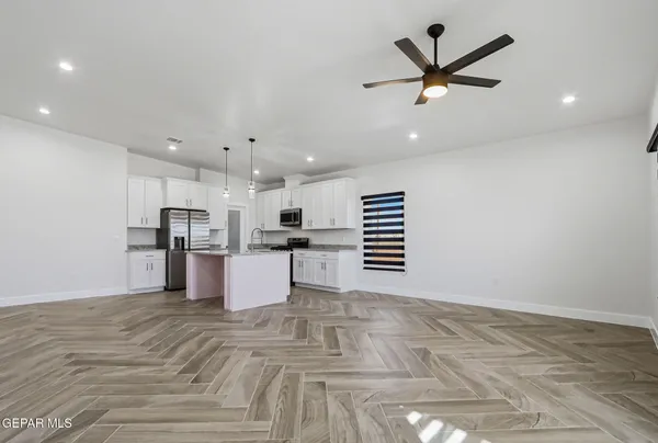 a view of kitchen with kitchen island white cabinets stainless steel appliances and window