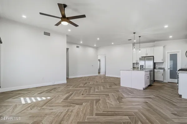 an empty room with windows and a chandelier fan