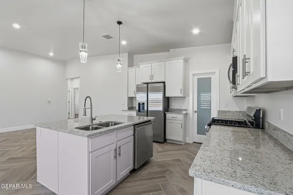 a kitchen with stainless steel appliances granite countertop a sink a stove and a refrigerator