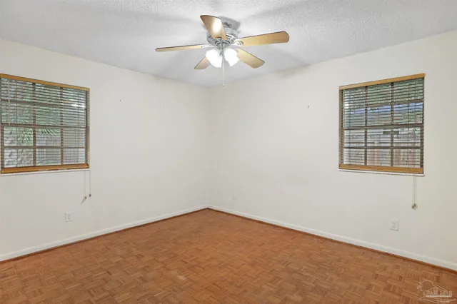 an empty room with windows and fan
