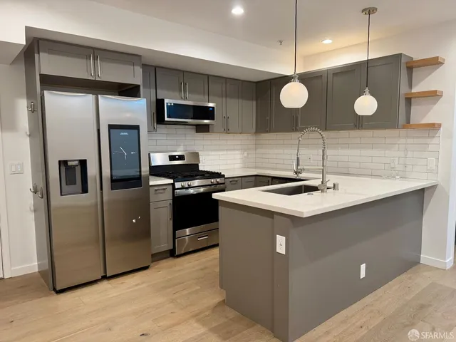 a kitchen with a sink stainless steel appliances a refrigerator and a wooden floor