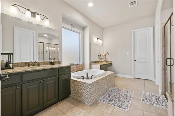 a spacious bathroom with a double vanity sink a mirror and a bathtub