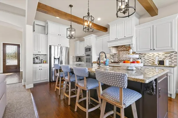 a kitchen with stainless steel appliances granite countertop a dining table chairs sink and cabinets