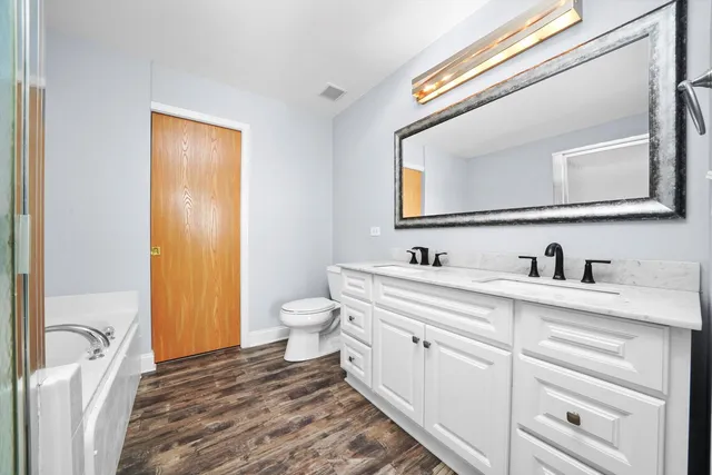 a bathroom with a granite countertop sink vanity mirror and toilet
