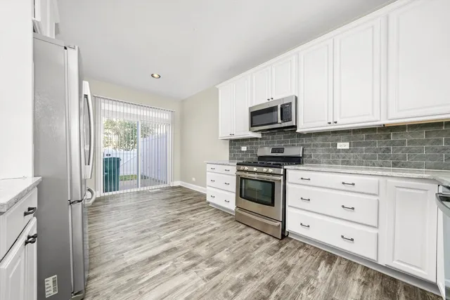a kitchen with granite countertop white cabinets and stainless steel appliances