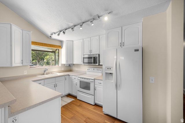 2088 Falcon Way Sandy, UT 84093 - Photo 10 of 46 Kitchen featuring white cabinetry, light countertops, wood-finish flooring, and a vaulted ceiling