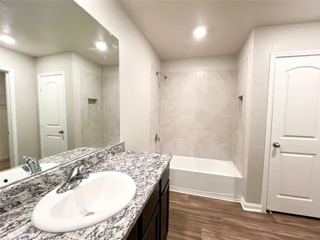 a bathroom with a granite countertop sink a mirror and a bathtub