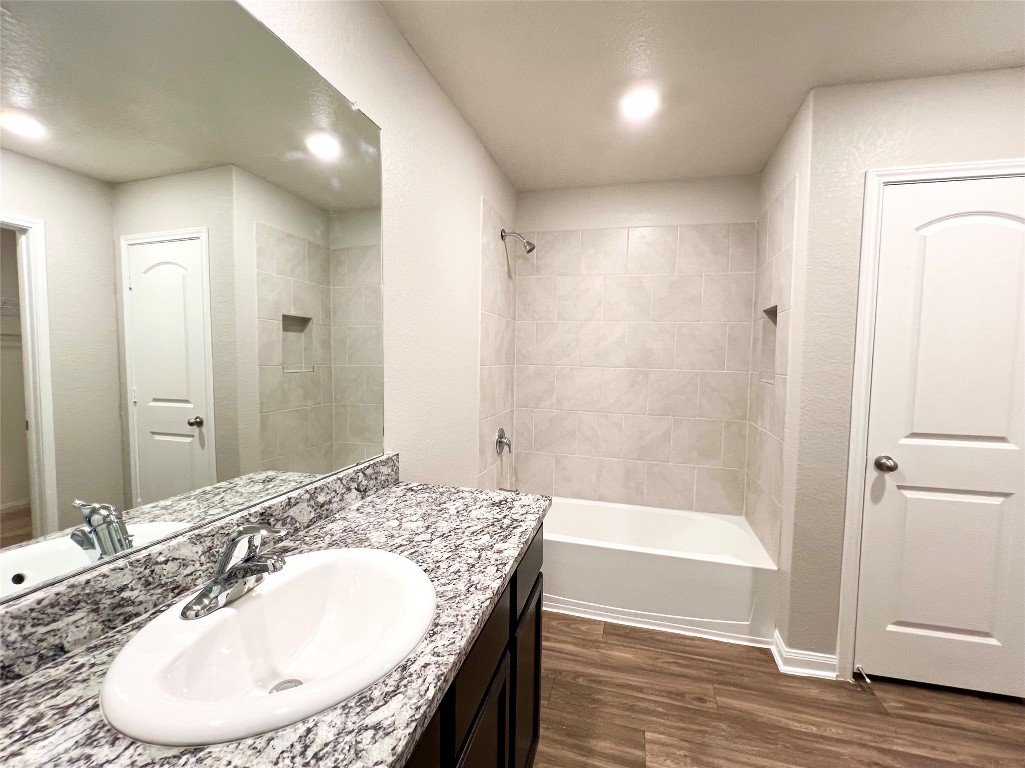 1033 Riverdale Cove Jarrell, TX 76537 - Photo 11 of 13 a bathroom with a granite countertop sink a mirror and a bathtub