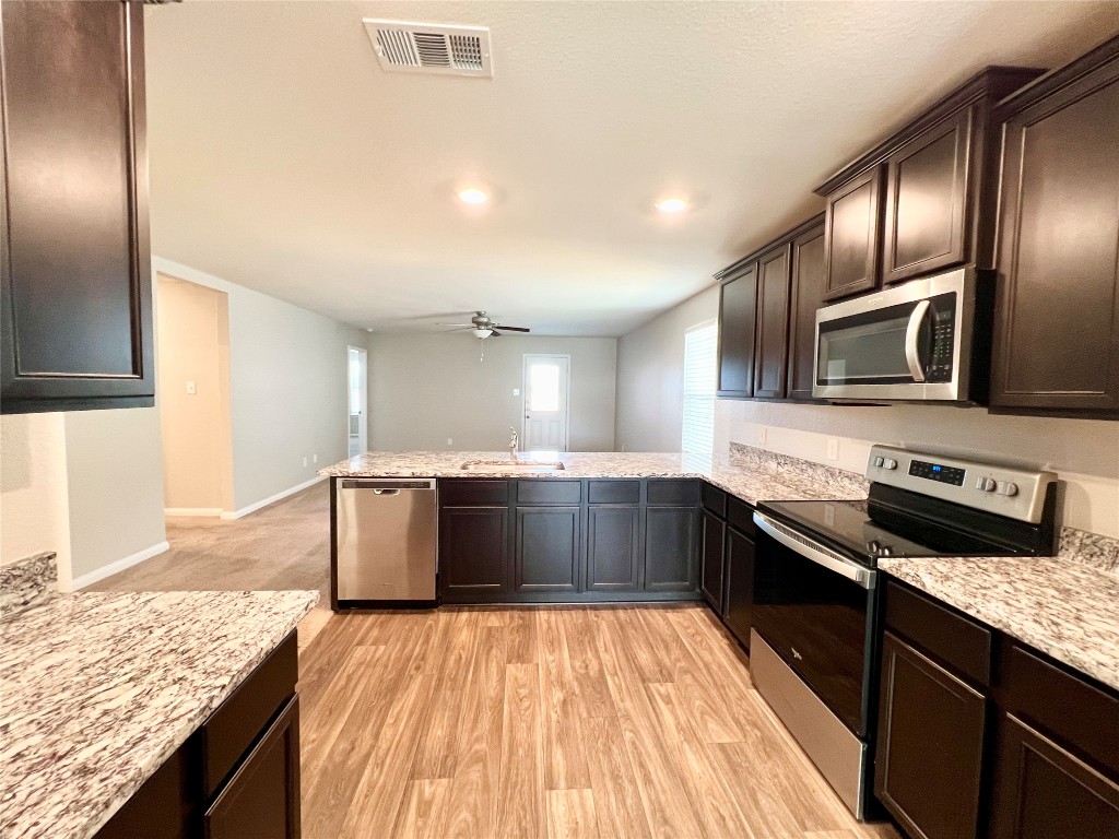 1033 Riverdale Cove Jarrell, TX 76537 - Photo 2 of 13 a kitchen with stainless steel appliances granite countertop a sink a stove top oven a counter space and cabinets