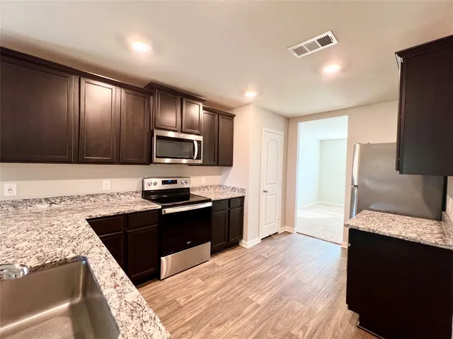 a kitchen with granite countertop stainless steel appliances and wooden cabinets
