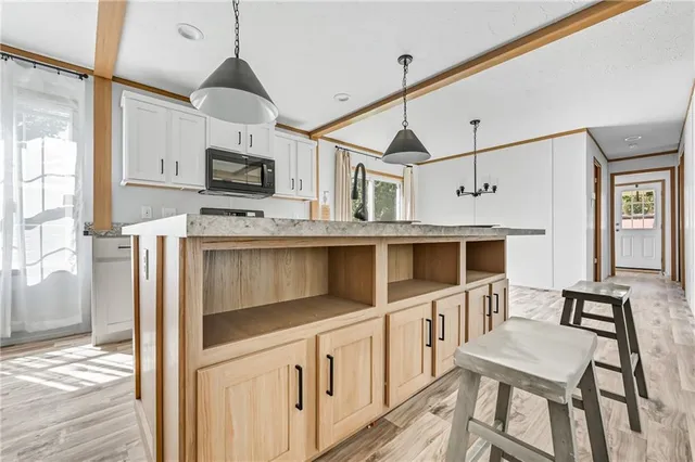 a kitchen with stainless steel appliances granite countertop a stove top oven a sink a microwave a dining table and chairs with wooden floor