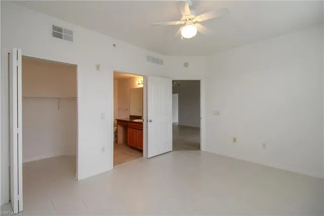 an empty room with windows and fan
