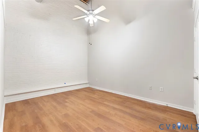 an empty room with a ceiling fan and wooden floor