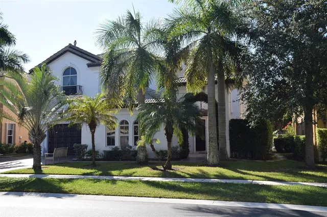 a view of a house with a yard and palm trees