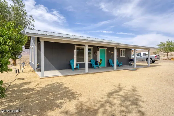 a view of a house with a barbeque and large trees