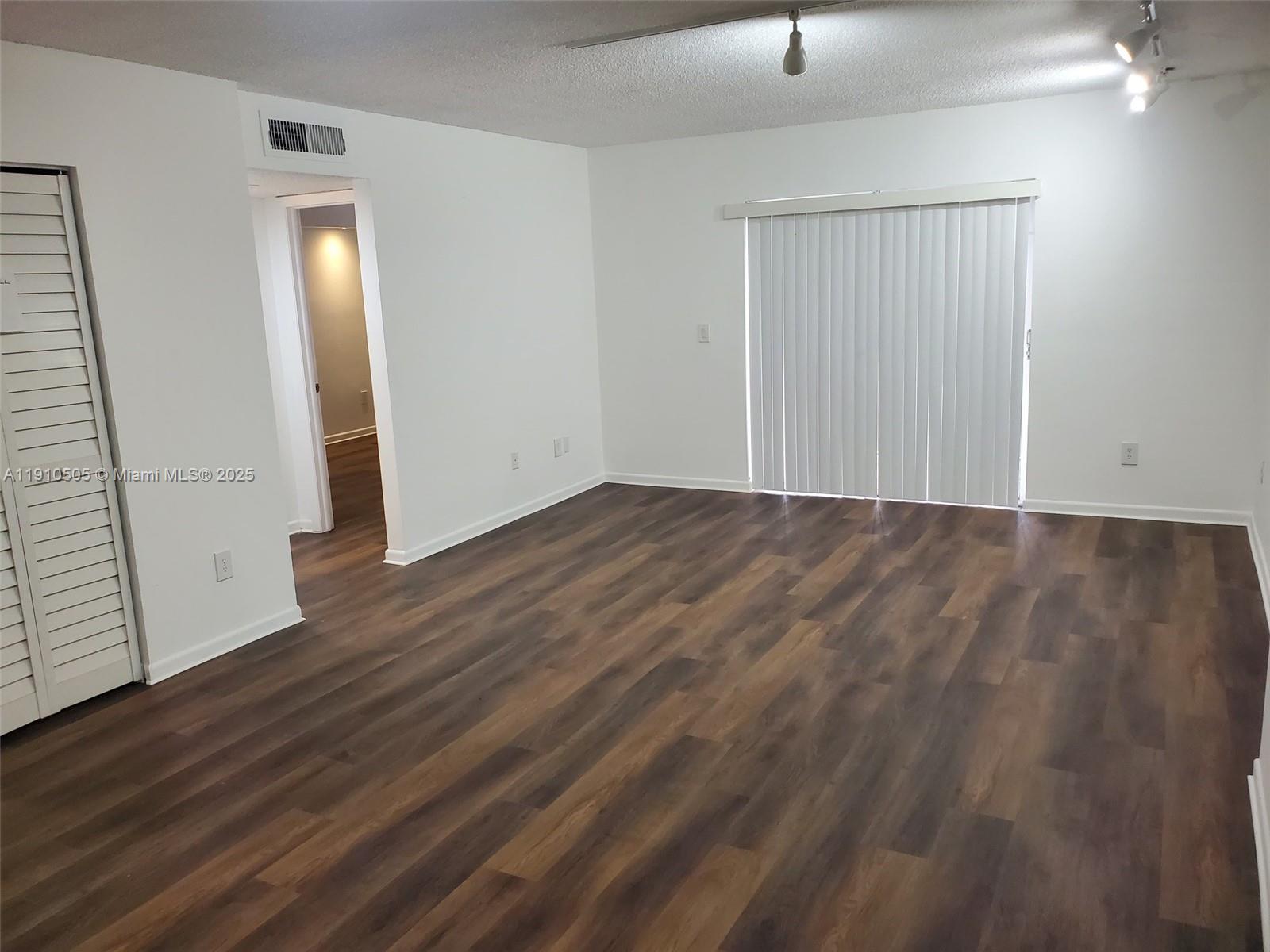 8260 Southwest 210th Street, Unit 217 Cutler Bay, FL 33189 - Photo 3 of 19 an empty room with wooden floor and mirror