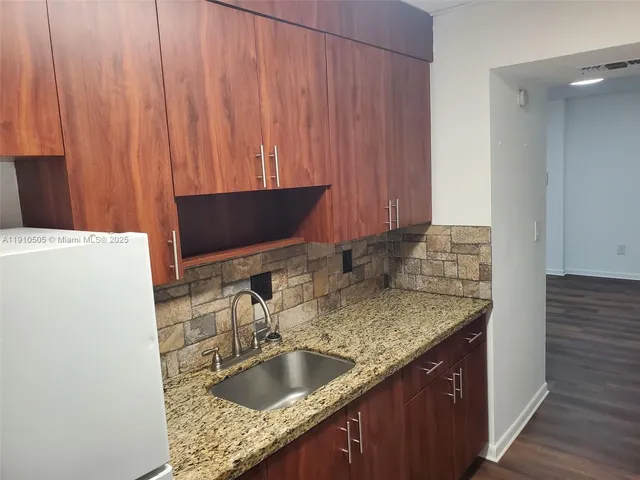 a kitchen with granite countertop a sink and a wooden cabinets