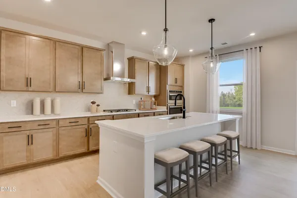 a large kitchen with cabinets chairs a sink and appliances