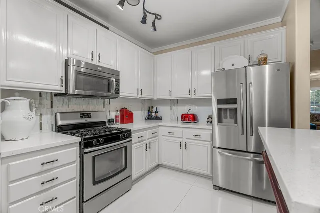 a kitchen with stainless steel appliances a refrigerator stove and white cabinets