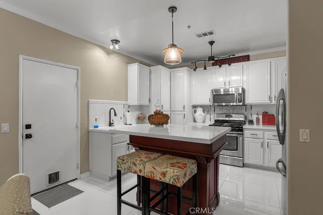 a kitchen with stainless steel appliances a table chairs refrigerator and microwave