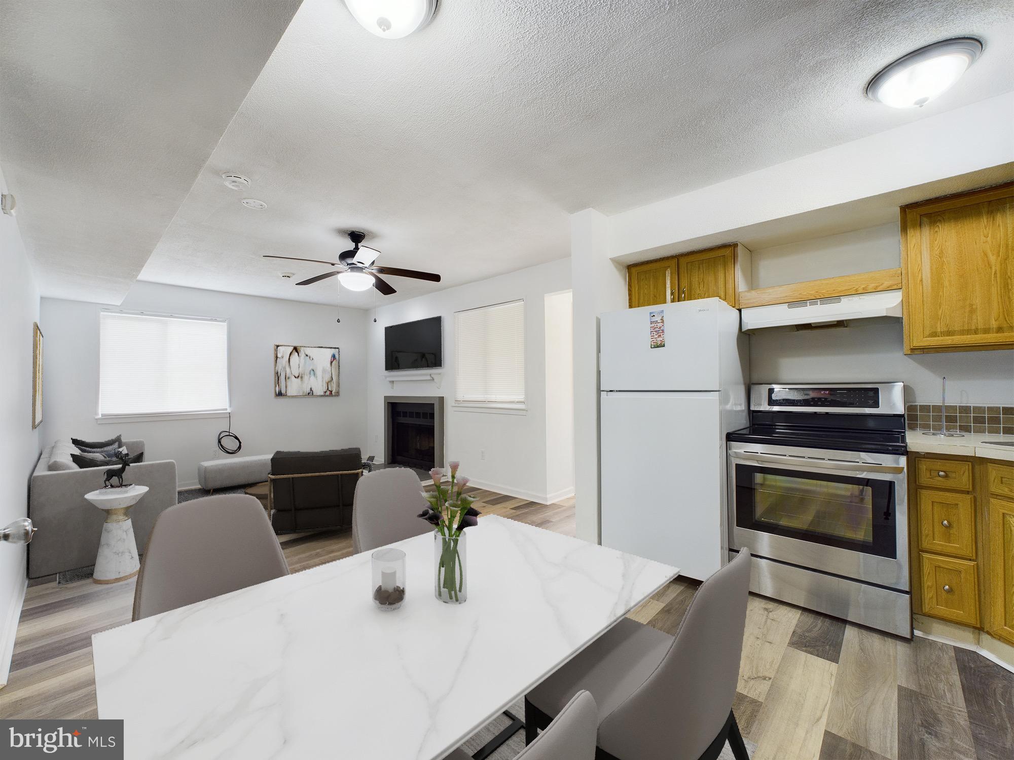 a kitchen with stainless steel appliances kitchen island granite countertop a refrigerator a stove a sink dishwasher a dining table and chairs with wooden floor