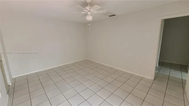 an empty room with white walls and ceiling fan