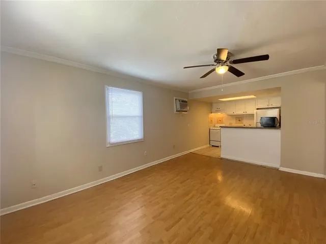 a view of empty room with wooden floor and ceiling fan
