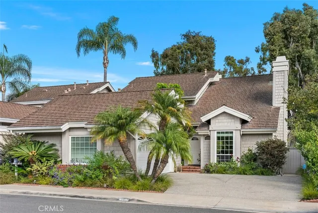 front view of a house with a yard and palm trees