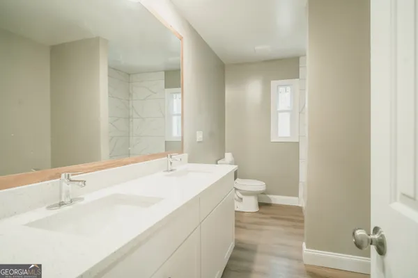 a bathroom with a granite countertop sink a toilet and a large mirror