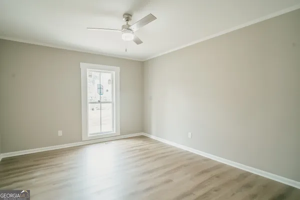 an empty room with wooden floor ceiling fan and windows