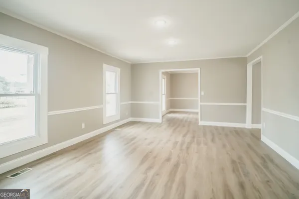 an empty room with wooden floor and windows