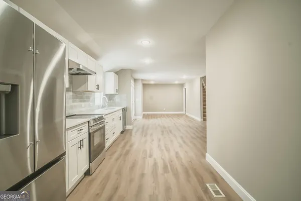 a large kitchen with cabinets wooden floor and stainless steel appliances