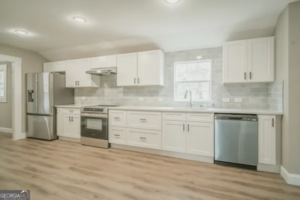 a kitchen with granite countertop white cabinets and stainless steel appliances