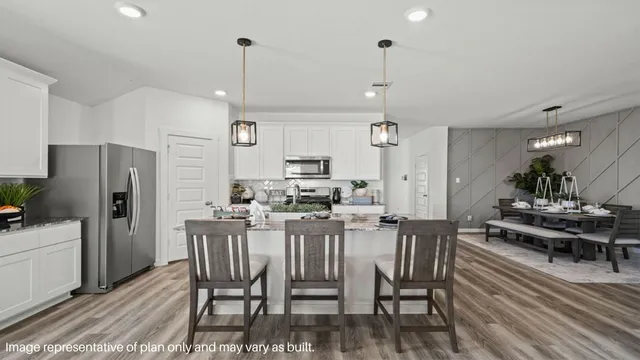 a kitchen with stainless steel appliances a dining table chairs refrigerator and sink