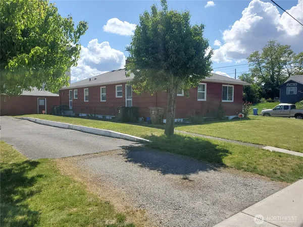 a view of a house with a yard and large tree