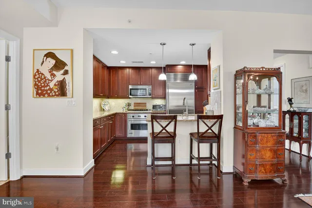 a kitchen with stainless steel appliances wooden floor and a refrigerator
