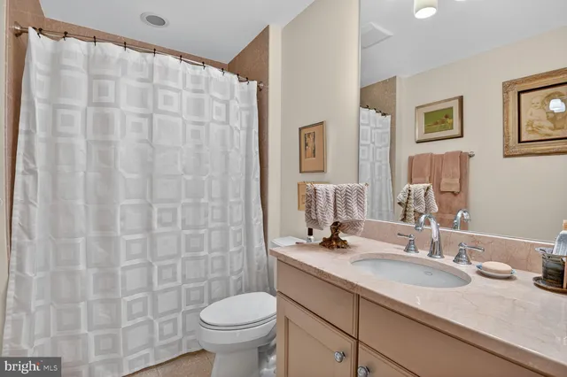 a bathroom with a granite countertop sink a toilet and a mirror