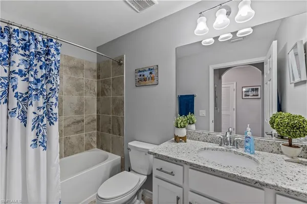 a bathroom with a granite countertop sink a toilet and bathtub