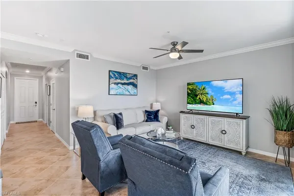 a living room with furniture a flat screen tv and a potted plant