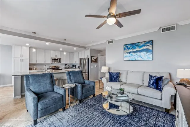 a living room with furniture kitchen view and a chandelier