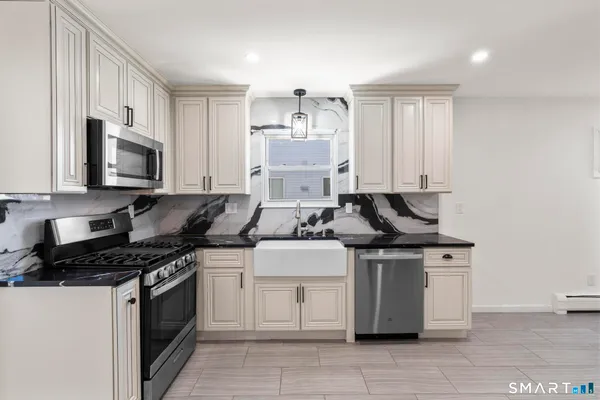 a kitchen with stainless steel appliances a stove and white cabinets
