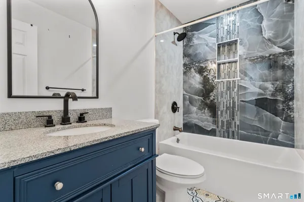 a bathroom with a granite countertop sink toilet and shower