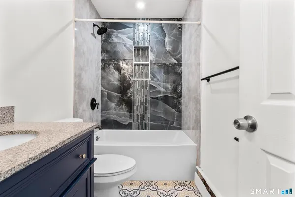 a bathroom with a granite countertop sink toilet and shower