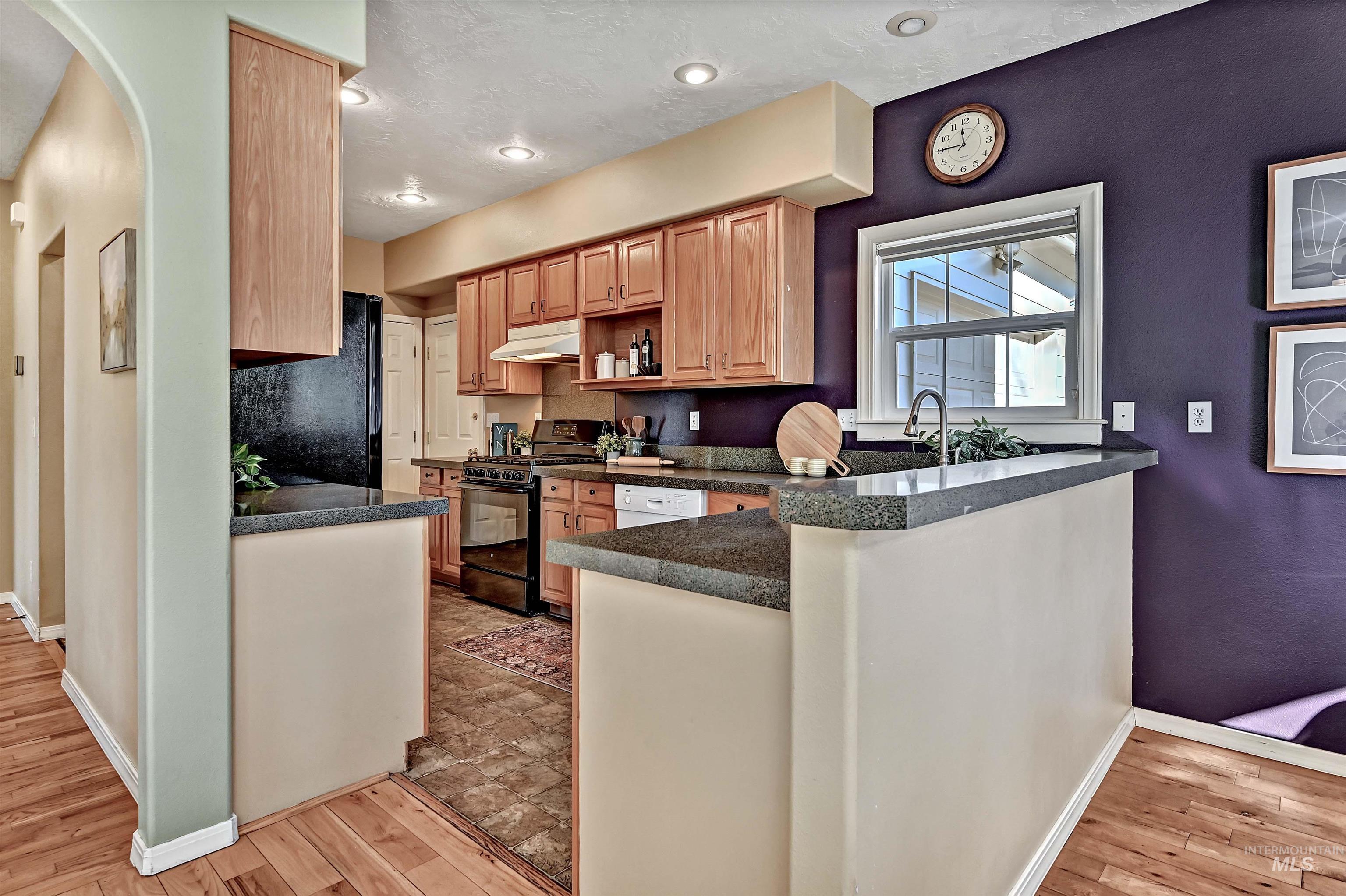 1902 West Washington Street Boise, ID 83702 - Photo 10 of 43 Kitchen with dark countertops, black appliances, light wood-style floors, and a peninsula