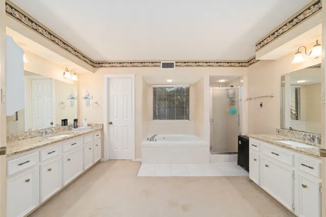 a spacious bathroom with a granite countertop sink a mirror a bathtub and shower