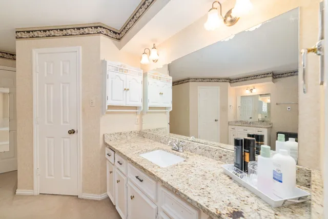 a bathroom with a granite countertop sink a mirror and shower