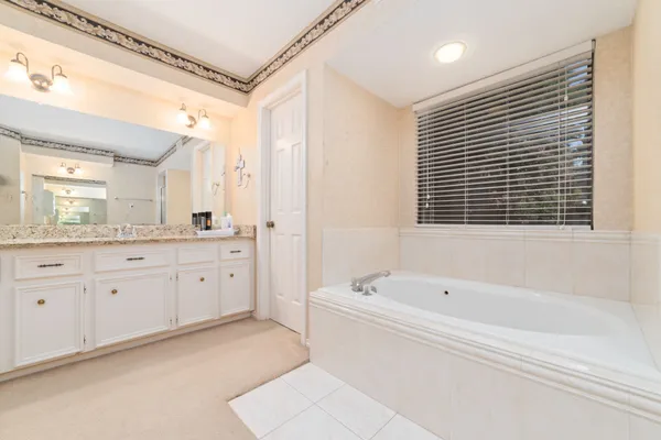 a spacious bathroom with a tub sink and mirror