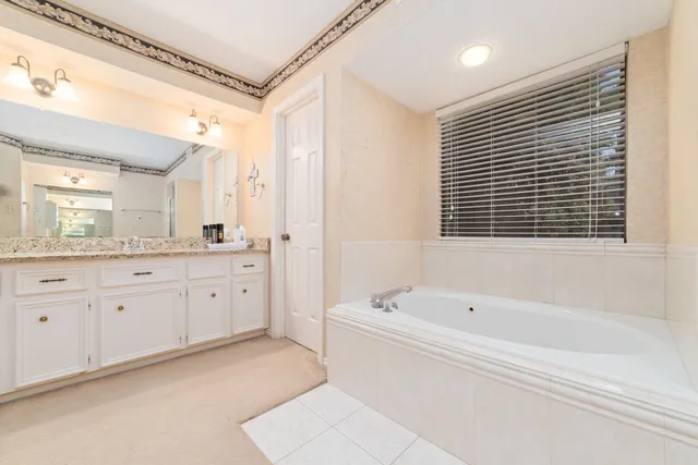 a spacious bathroom with a tub sink and mirror