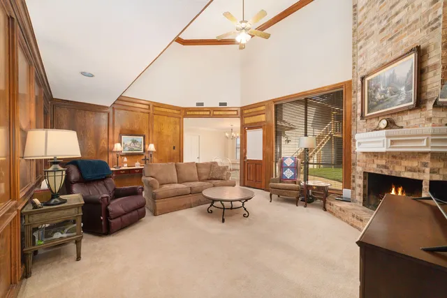 a living room with furniture a fireplace and floor to ceiling windows